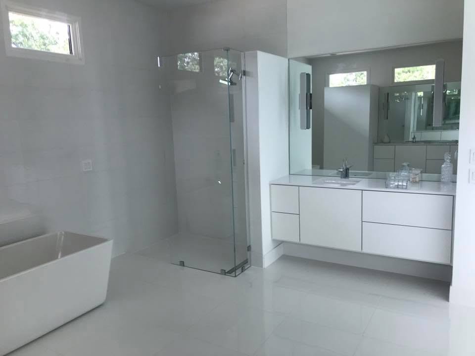 Latham Cabinets project photo: white custom floating bathroom vanity with drawer storage beneath a stone countertop and full-width mirror